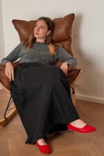 רודה חולצה אינה מראה אופנה נוחה ללבוש, ישיבה נינוחה על כיסא עור חום.