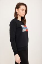 עלי עט על רקע לבן, בספורט סווטשירט שחורה עם עיצוב צבעוני על החזה, אופנה נוחה ללבוש.