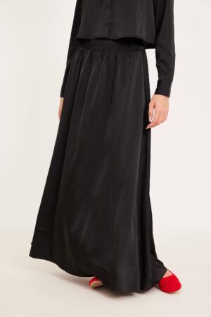 מתאים לבגדי אופנה נוחים ללבוש, חצאית שחורה ארוכה עם גומי במותן, ואישה לובשת חולצה שחורה ונעלי אדום.