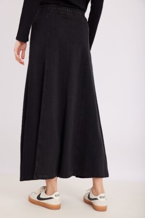 רק פינת אחורית של חצאית ג'ינס שחורה ארוכה לנשים, עם עקב קלאסי וסטייל נשי שיק.