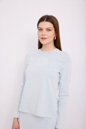 רקע לבן, אישה יושבת לבושי בגדי אופנה נוחים ואלגנטיים, הלבשה של אופנה שדורשת נוחות, תודעת אופנה גבוהה, סגנון מודרני, והנאה מהלבשה.